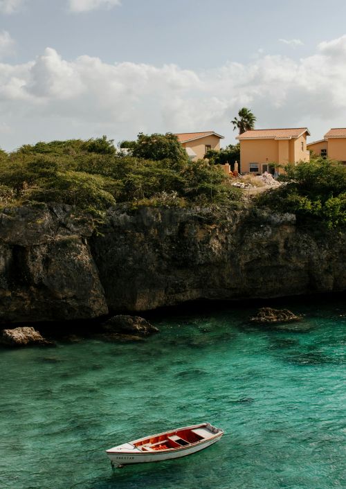 Clear water river beneath the edge of a cliff with houses on the cliff